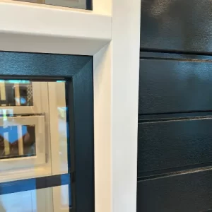 Wit kunststof kozijn met een donker draaideel tegen donker keralit